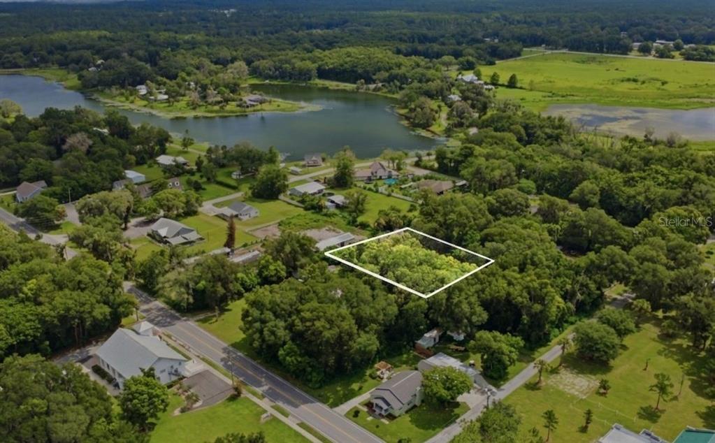 An aerial view shows a rectangular, tree-covered vacant lot outlined in white near a lake — S LAKEVIEW DRIVE, LAKE HELEN, FL