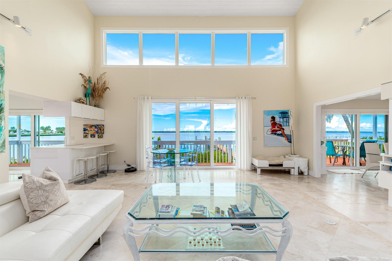 A bright living room with high ceilings, tile floors, and large windows overlooking the water — 1470 SE Macarthur Boulevard, Stuart FL 34996, STUART, FL