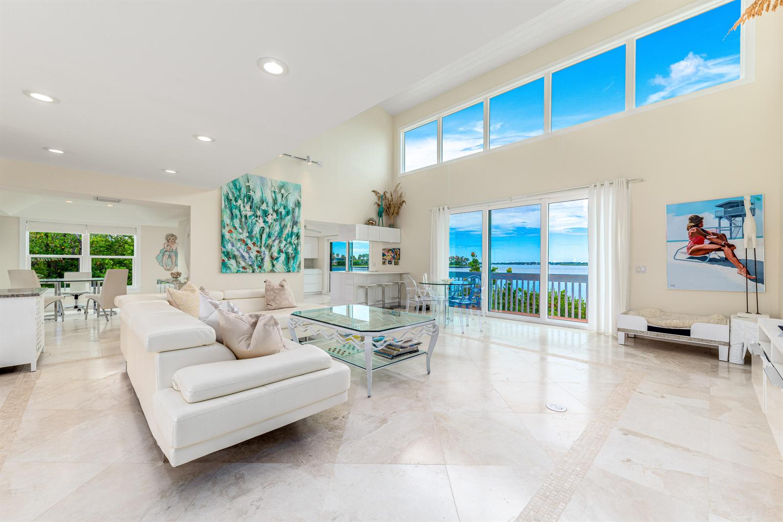 A bright, open-concept living room with white tile floors, high ceilings, and waterfront balcony views — 1470 SE Macarthur Boulevard, Stuart FL 34996, STUART, FL