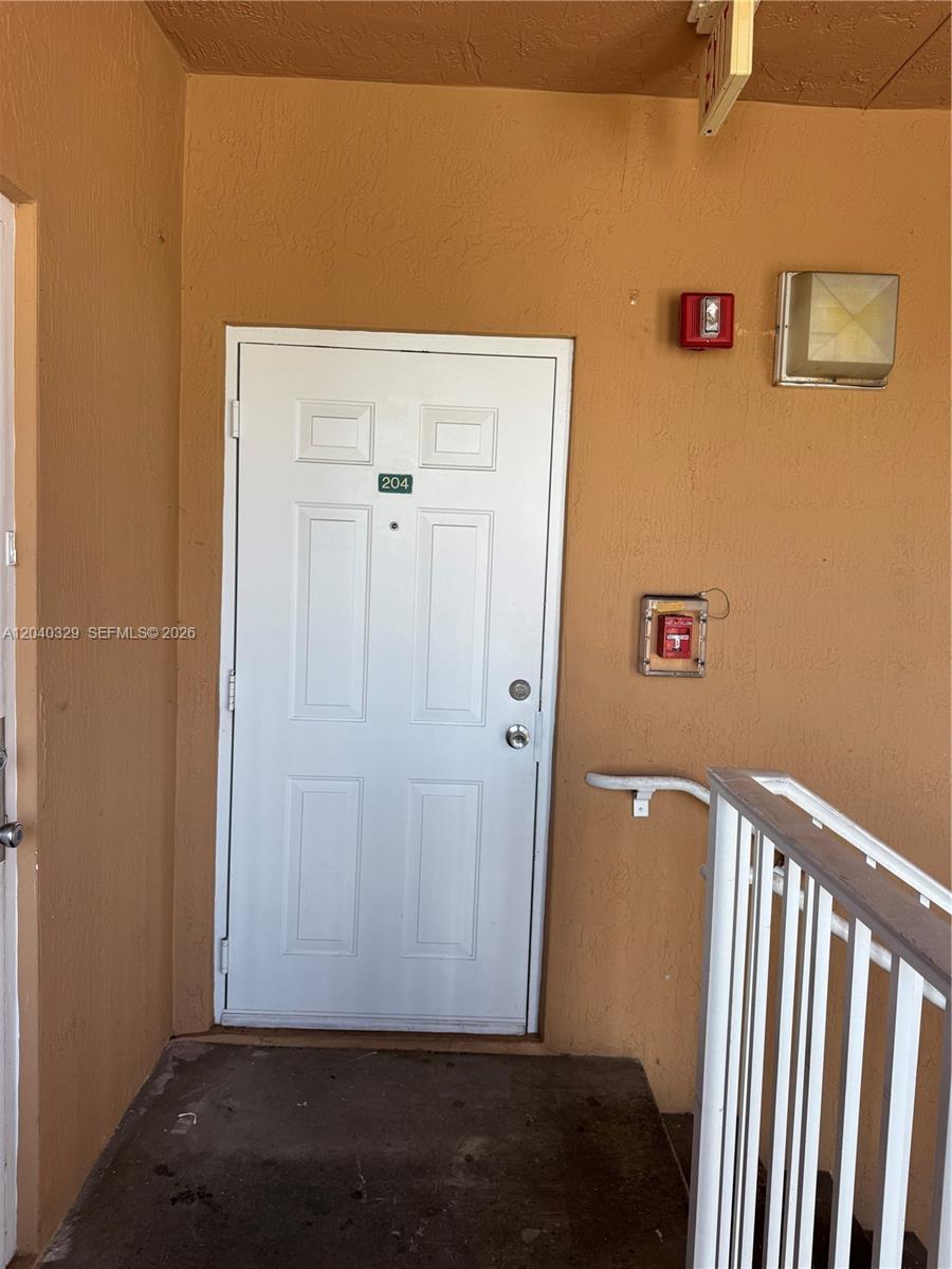 A white door labeled 204 is set into a tan exterior wall with fire safety equipment — 17640 NW 73rd Ave # 19, Hialeah FL 33015, HIALEAH, FL