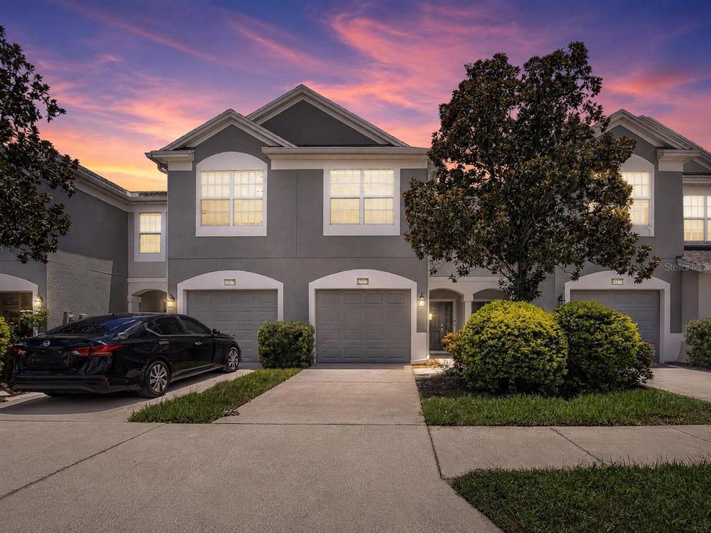A two-story townhouse exterior with gray siding, a concrete driveway, and a black sedan — 10137 PINK PALMATA COURT, RIVERVIEW, FL