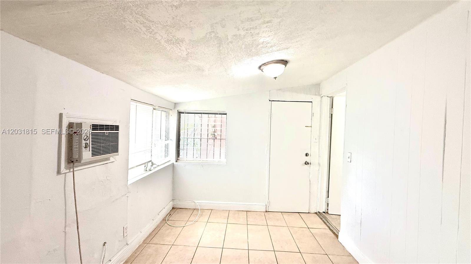 A small room with white walls, tiled floors, a window air conditioner, and a door — 1878 NW 112th Ter # 1, Miami FL 33167, MIAMI, FL