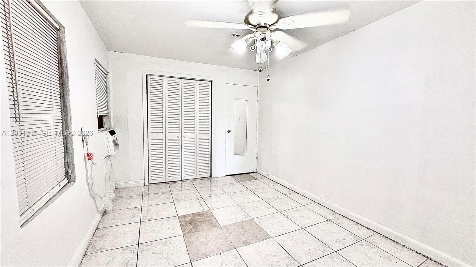A room with white walls, tiled floors, a ceiling fan, and a louvered closet door — 1878 NW 112th Ter # 1, Miami FL 33167, MIAMI, FL