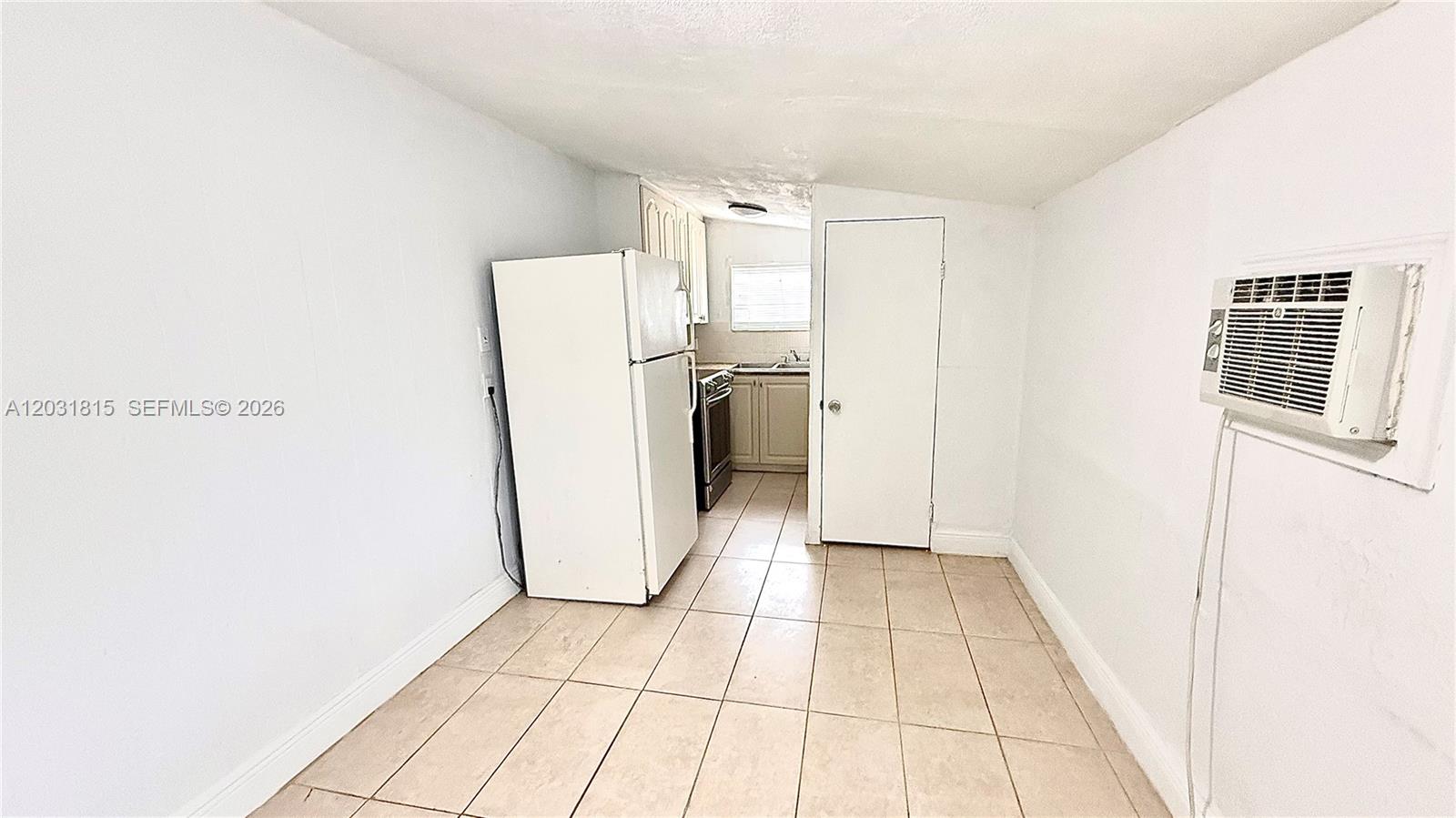 A small kitchen features white appliances, light-colored cabinets, and beige tile flooring — 1878 NW 112th Ter # 1, Miami FL 33167, MIAMI, FL