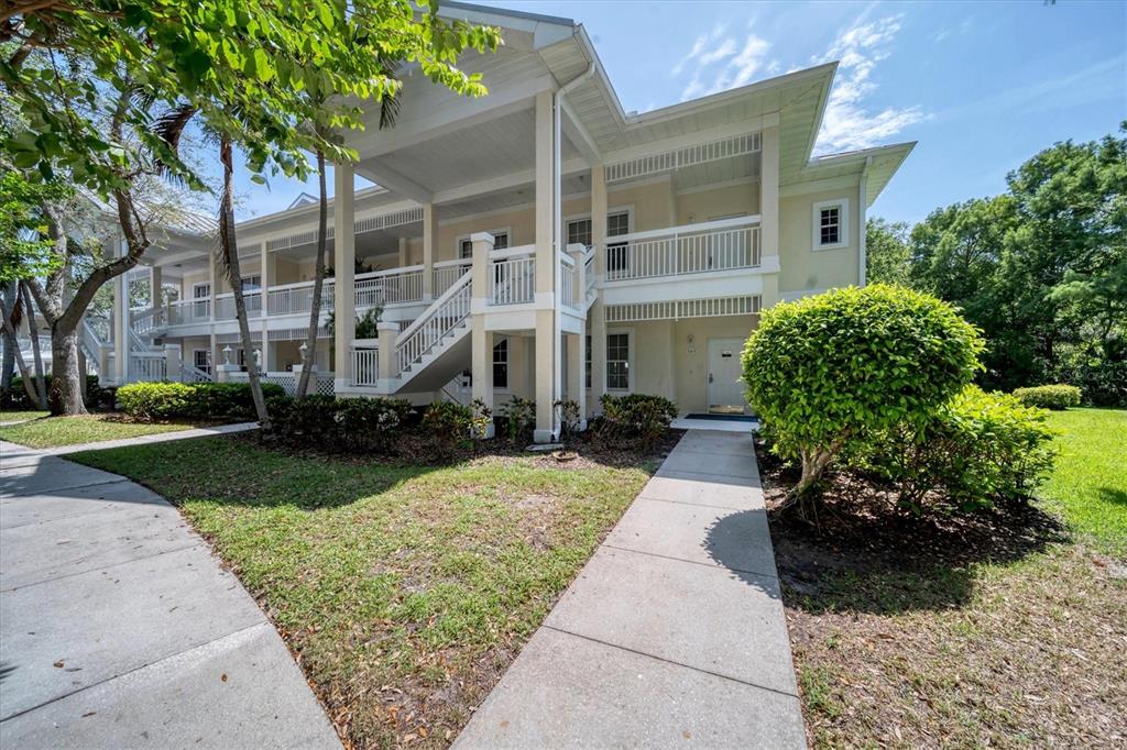 A two-story light yellow building with a covered staircase and a concrete walkway — 3604 54TH DRIVE W UNIT 102, BRADENTON, FL