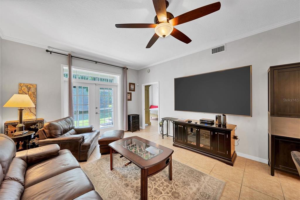 A living room features tile floors, a ceiling fan, leather furniture, and a large television — 3604 54TH DRIVE W UNIT 102, BRADENTON, FL