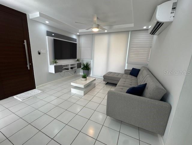 A modern living room features white tile floors, a gray sectional sofa, and a wall-mounted television — A VISTA REAL UNIT 10, FAJARDO, PR
