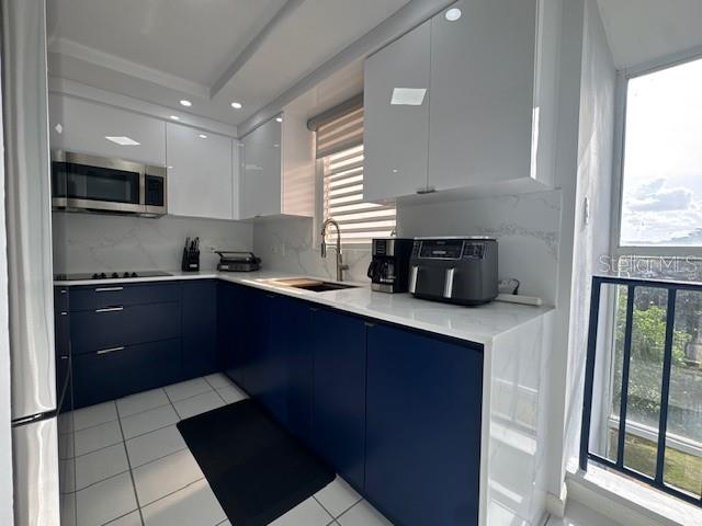 A modern kitchen features white upper cabinets, dark blue lower cabinets, and white countertops — A VISTA REAL UNIT 10, FAJARDO, PR
