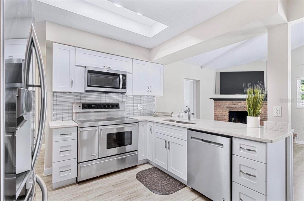 A modern kitchen features white cabinets, stainless steel appliances, and a light-colored countertop — 5127 CAESAR WAY S, ST PETERSBURG, FL