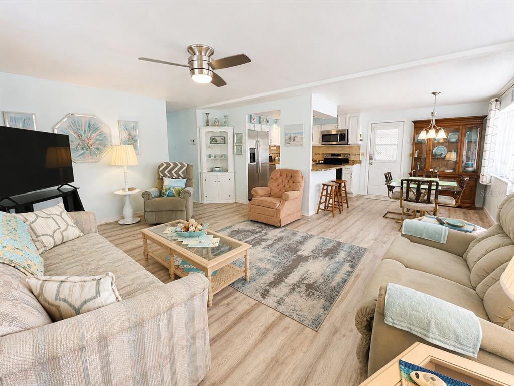 A living room with light wood flooring, a ceiling fan, and an open kitchen area — 1614 MICHIGAN AVENUE, BRADENTON, FL