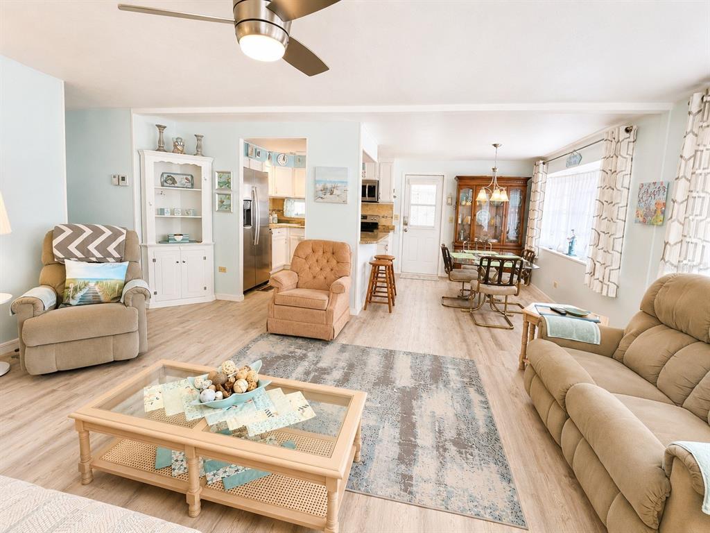 A living room and dining area feature light wood flooring, neutral furniture, and a ceiling fan — 1614 MICHIGAN AVENUE, BRADENTON, FL