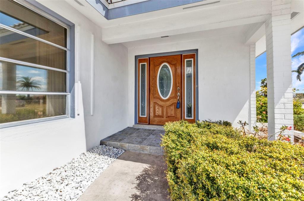 A wooden front door with a glass oval insert sits under a covered entryway — 2350 W MARION AVENUE, PUNTA GORDA, FL