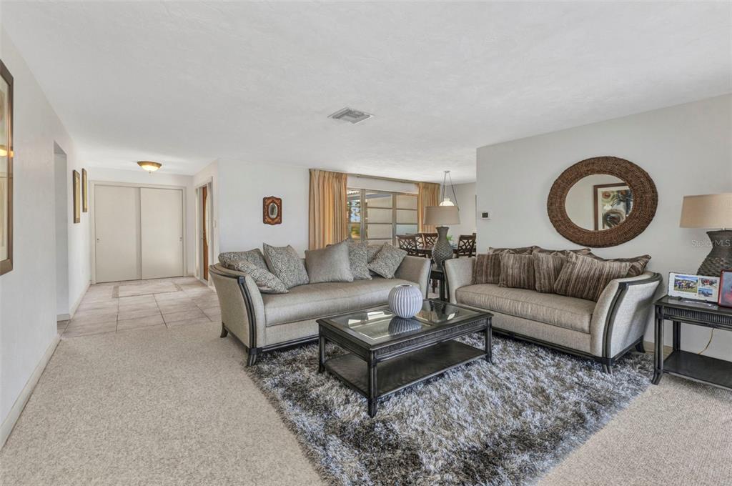 A living room features two sofas, a coffee table, a rug, and a round mirror — 2350 W MARION AVENUE, PUNTA GORDA, FL