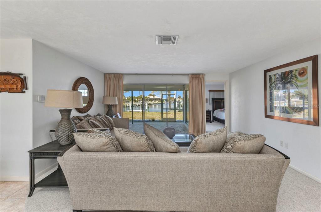 A living room with a sofa facing a sliding glass door that overlooks a canal — 2350 W MARION AVENUE, PUNTA GORDA, FL