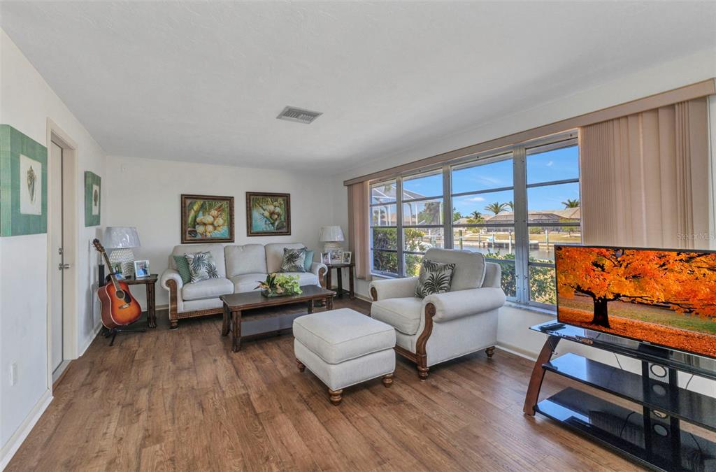A living room features wood-look flooring, a sofa, an armchair with an ottoman, and a television — 2350 W MARION AVENUE, PUNTA GORDA, FL