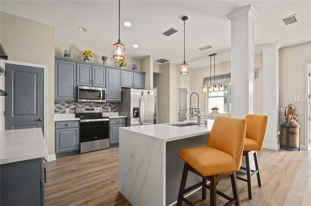 A kitchen features gray cabinets, a white quartz island, and two orange bar stools — 331 EASTERN AVENUE, ST CLOUD, FL