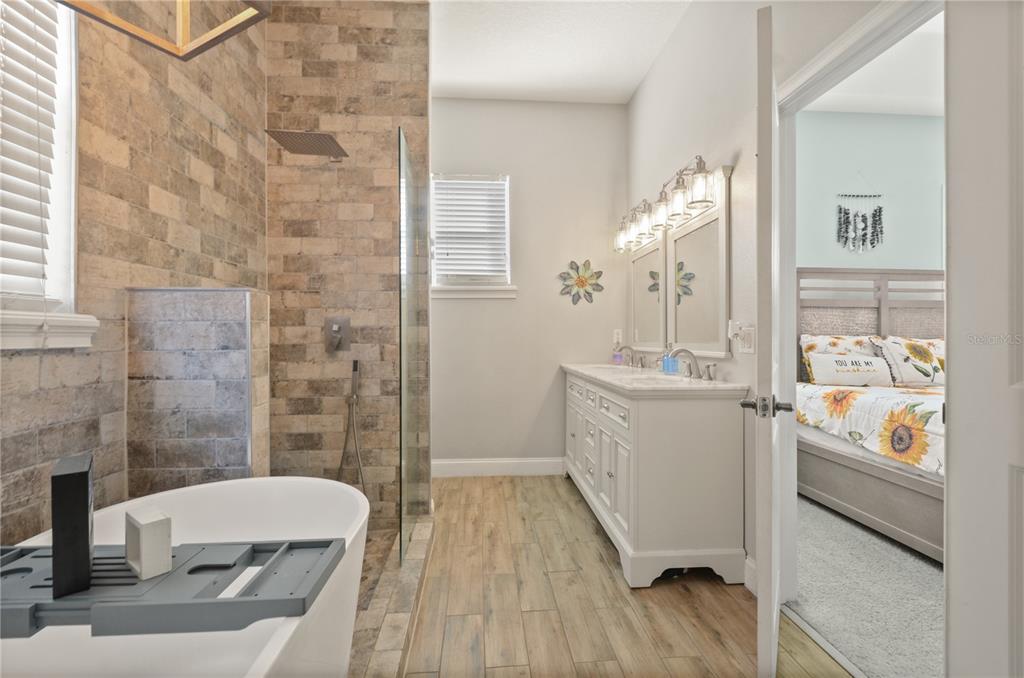 A bathroom features a freestanding tub, a walk-in shower with stone tile, and a double vanity — 331 EASTERN AVENUE, ST CLOUD, FL