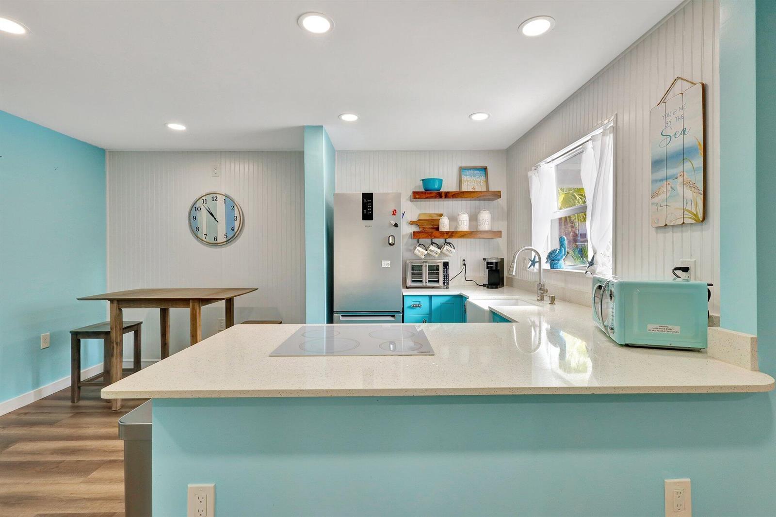 A kitchen with light blue walls, white beadboard, a quartz countertop, and stainless steel appliances — 11000 S Ocean Drive # 1d, Jensen Beach FL 34957, JENSEN BEACH, FL