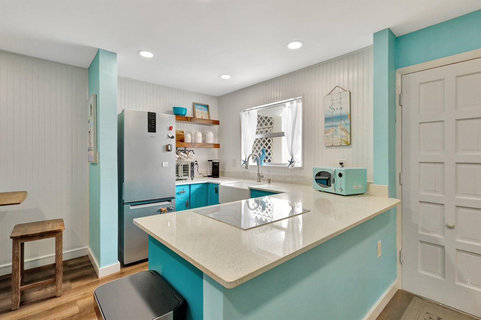A kitchen features teal cabinets, a light-colored quartz countertop, and a stainless steel refrigerator — 11000 S Ocean Drive # 1d, Jensen Beach FL 34957, JENSEN BEACH, FL