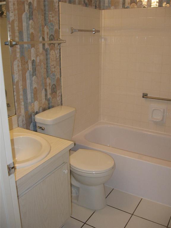 A bathroom features a white vanity, a toilet, and a bathtub with beige tiled walls — 2465 NORTHSIDE DRIVE UNIT 603, CLEARWATER, FL