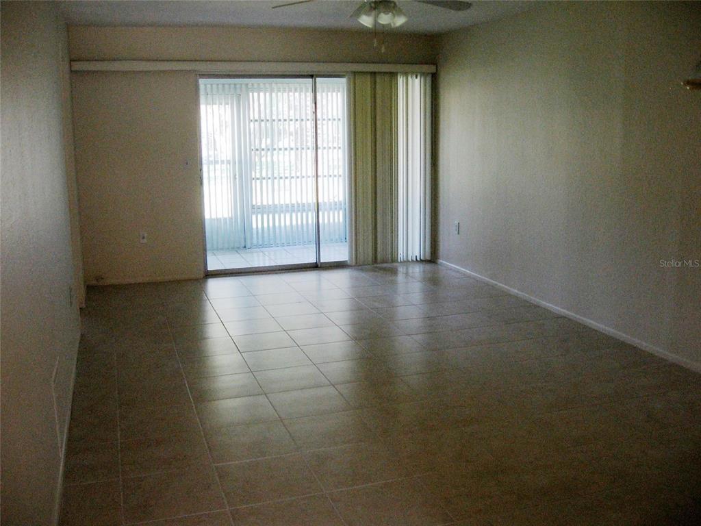 A living room with beige tile flooring and sliding glass doors leading to a patio — 2465 NORTHSIDE DRIVE UNIT 603, CLEARWATER, FL
