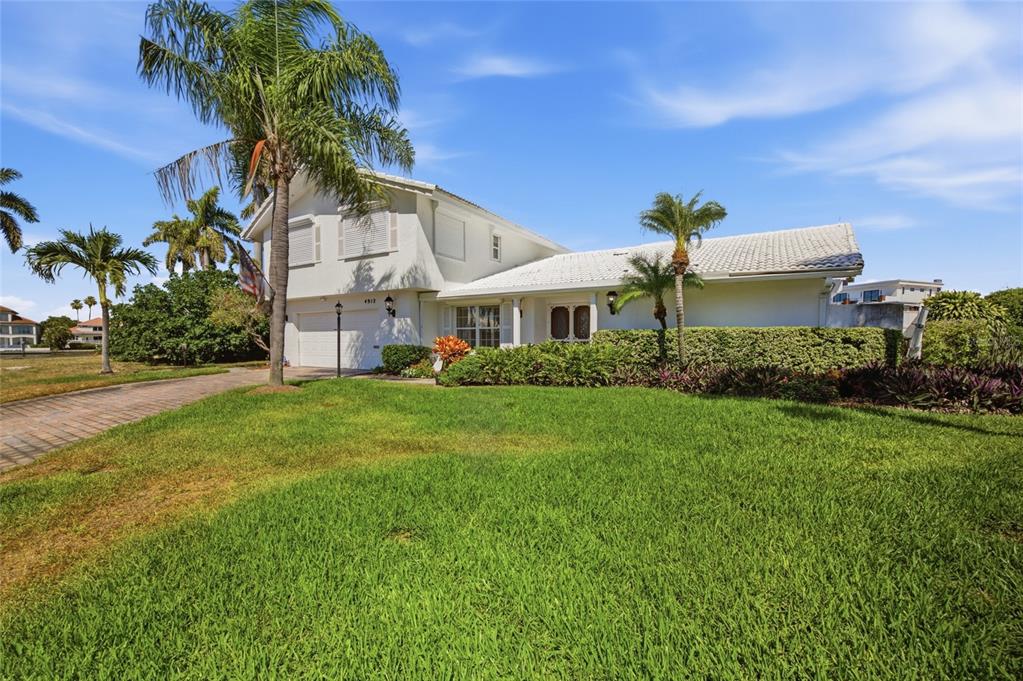 A two-story white house with a tiled roof, palm trees, and a green lawn — 4912 58TH AVENUE S, ST PETERSBURG, FL