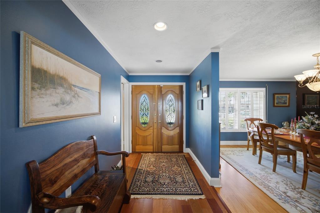 An entryway with blue walls, a wooden bench, and double doors leads into a dining room — 4912 58TH AVENUE S, ST PETERSBURG, FL