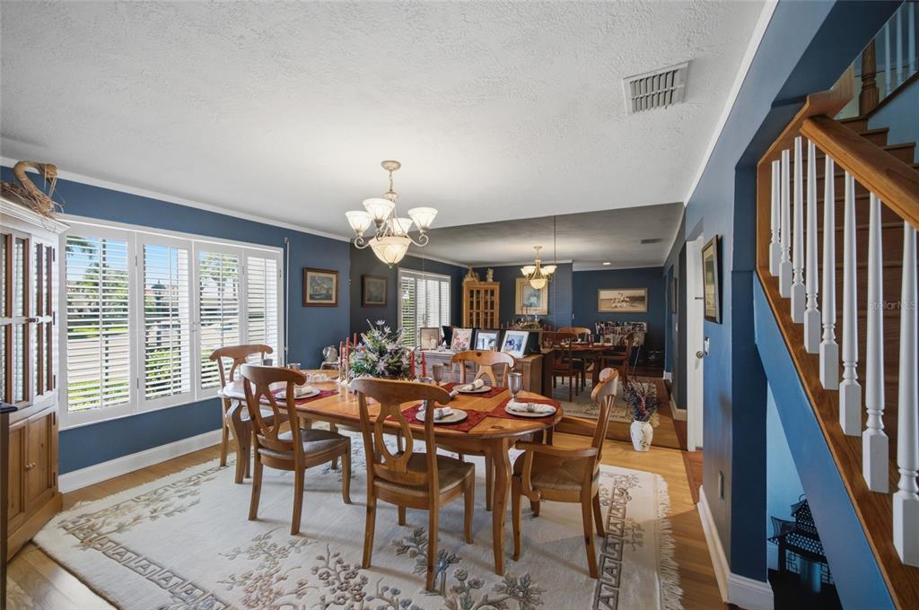 A dining room with blue walls, a wooden table, and a staircase with white railings — 4912 58TH AVENUE S, ST PETERSBURG, FL