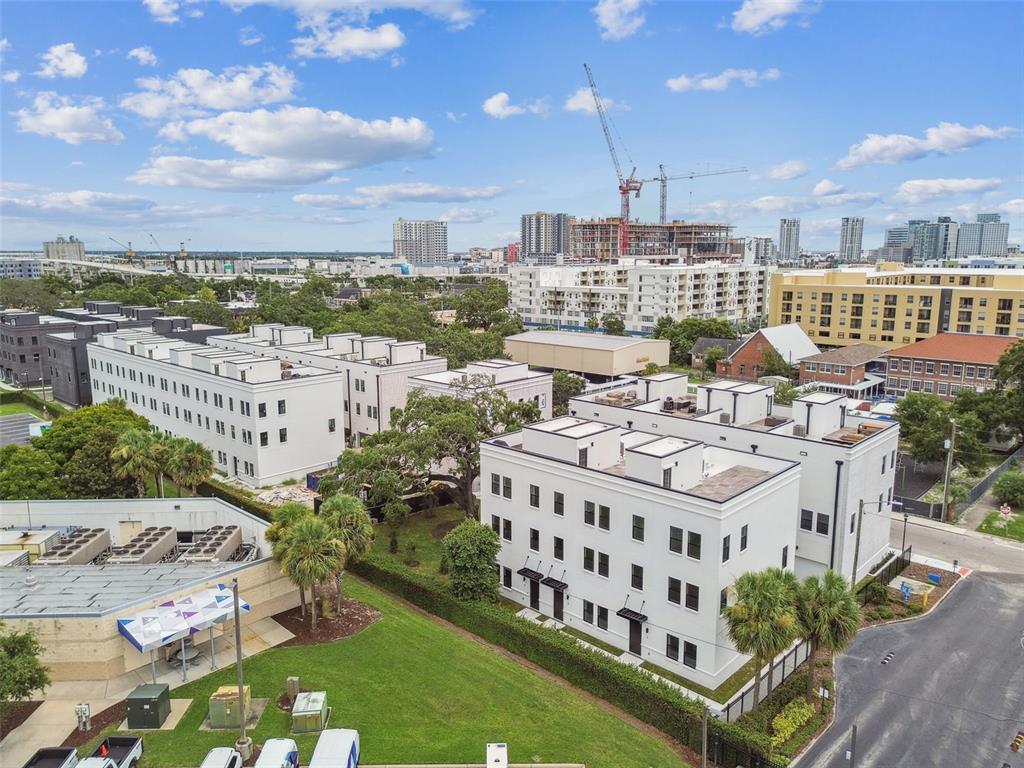 An aerial view shows modern white multi-story apartment buildings surrounded by trees and urban development — 1218 E KAY STREET UNIT 18, TAMPA, FL