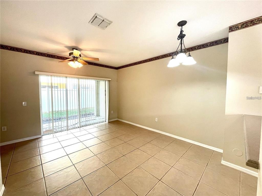 A living room features beige walls, a tile floor, a ceiling fan, and sliding glass doors — 8508 BRUSHLEAF WAY, TAMPA, FL