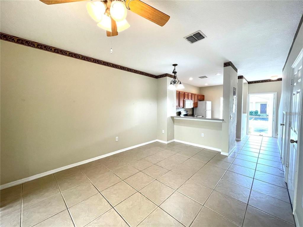 An open dining area features beige walls, tile flooring, a ceiling fan, and a breakfast bar — 8508 BRUSHLEAF WAY, TAMPA, FL