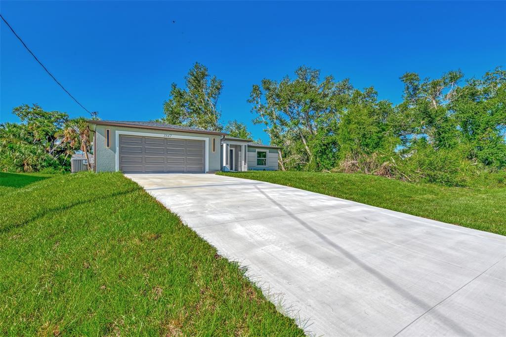 A single-story house with a gray garage and a concrete driveway under a clear sky — 4582 ENID LANE, NORTH PORT, FL