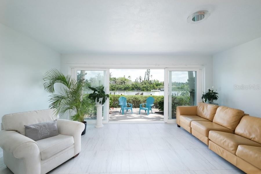 A living room with light tile floors, a tan leather sofa, and sliding glass doors — 6700 GULF OF MEXICO DRIVE UNIT 118, LONGBOAT KEY, FL
