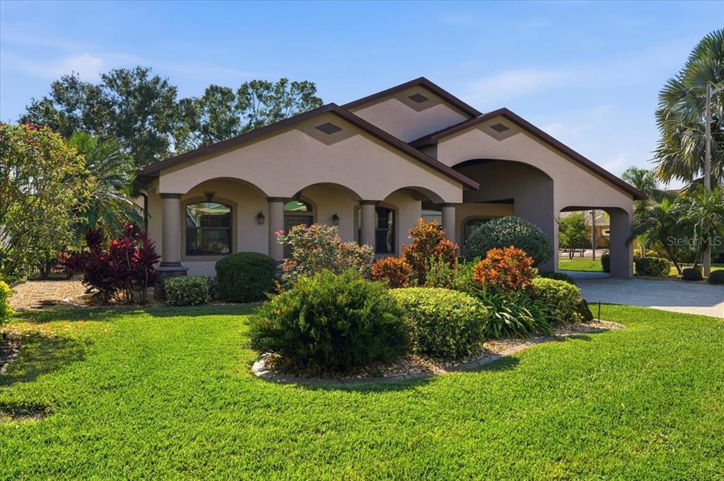 A single-story house with a covered entryway, arched columns, and a landscaped front yard — 584 MEANDERING WAY, POLK CITY, FL