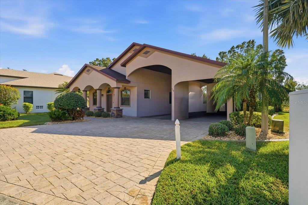 A single-story house features a large paved driveway, a covered carport, and a front porch — 584 MEANDERING WAY, POLK CITY, FL