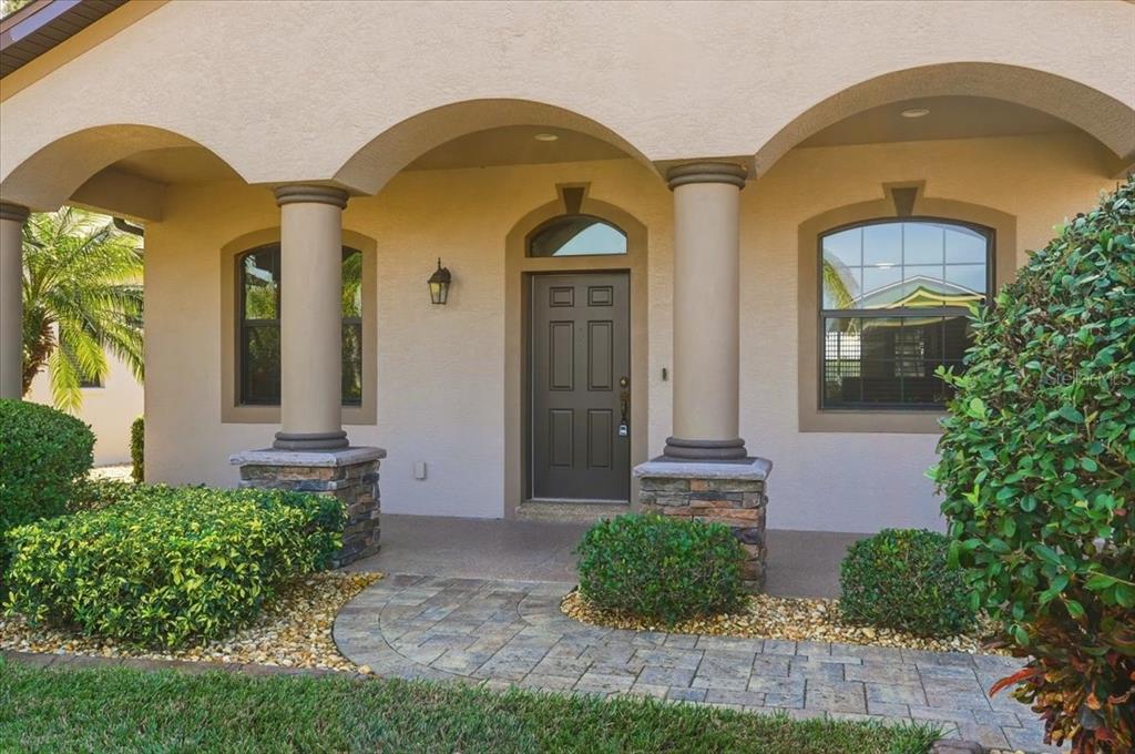 A front entryway features a dark door, arched columns, and a stone-paved walkway — 584 MEANDERING WAY, POLK CITY, FL