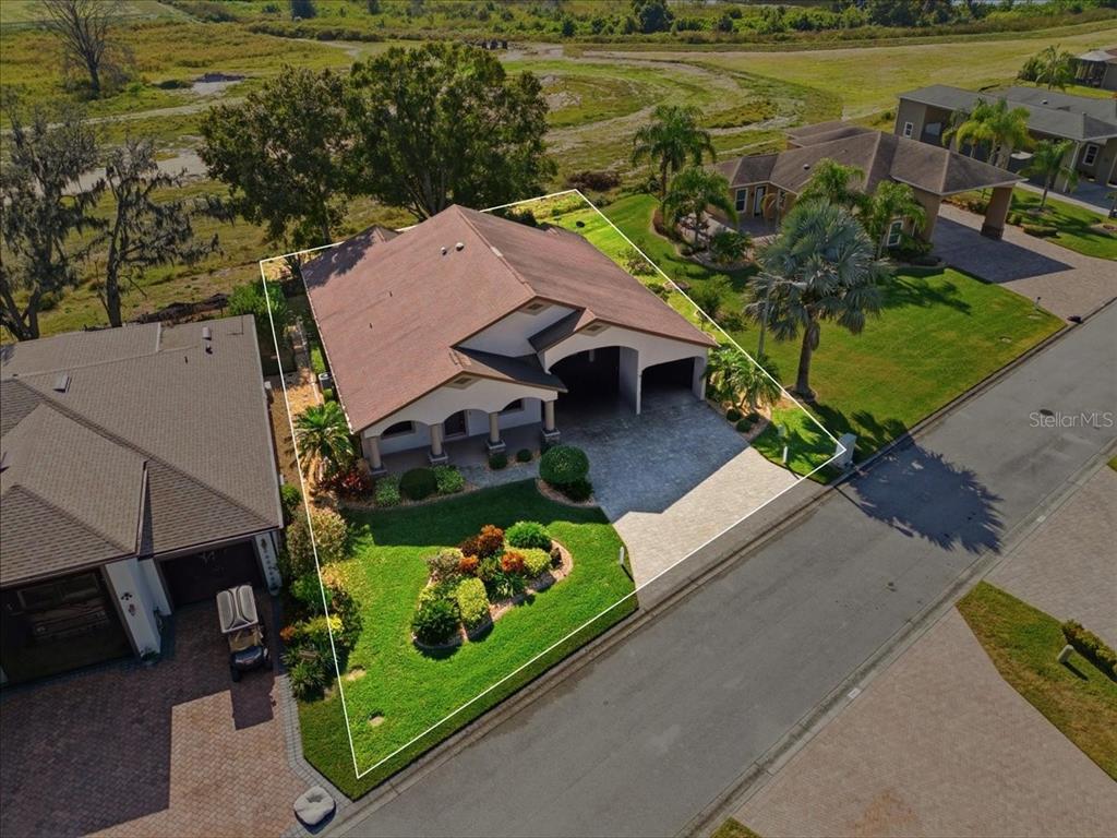 An aerial view shows a single-story house with a brown roof, paved driveway, and landscaping — 584 MEANDERING WAY, POLK CITY, FL