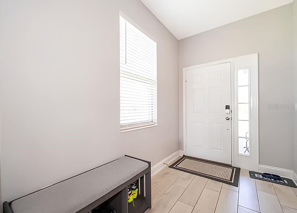 An entryway features light gray walls, tile flooring, a window with blinds, and a storage bench — 1881 NAPOLI DRIVE, ST CLOUD, FL