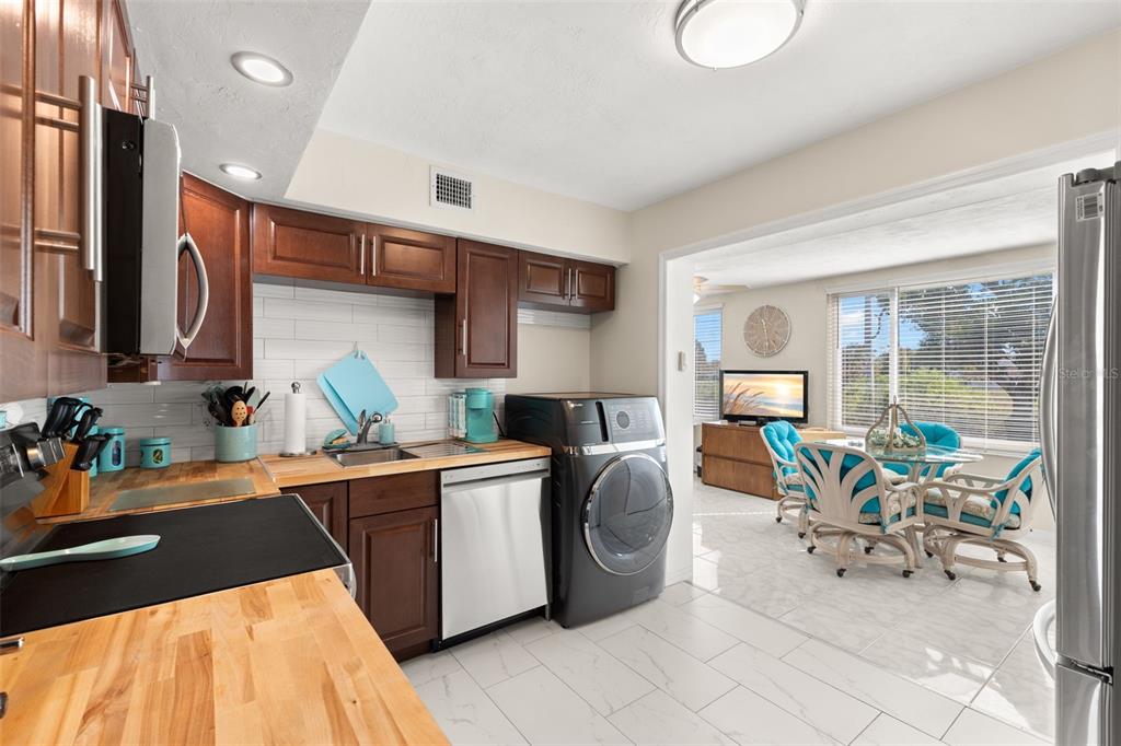 A dining area with a glass table and turquoise chairs opens into a kitchen — 2461 CANADIAN WAY UNIT 27, CLEARWATER, FL