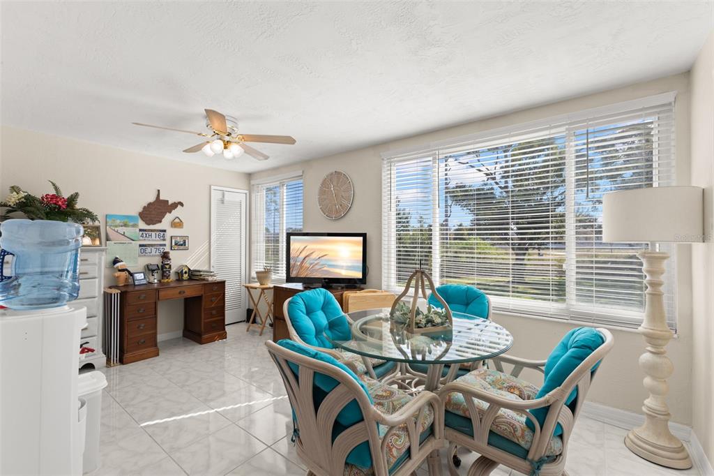 A living room with a white sofa, a brown area rug, and a dining area — 2461 CANADIAN WAY UNIT 27, CLEARWATER, FL