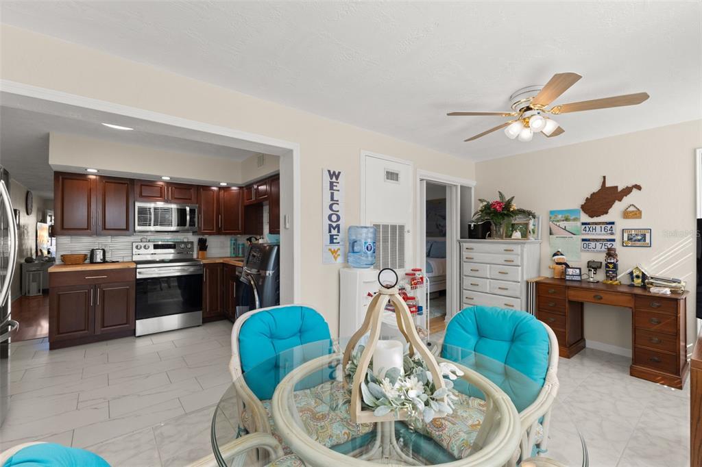 A dining area features a glass-topped table, wicker chairs with blue cushions, and tile flooring — 2461 CANADIAN WAY UNIT 27, CLEARWATER, FL
