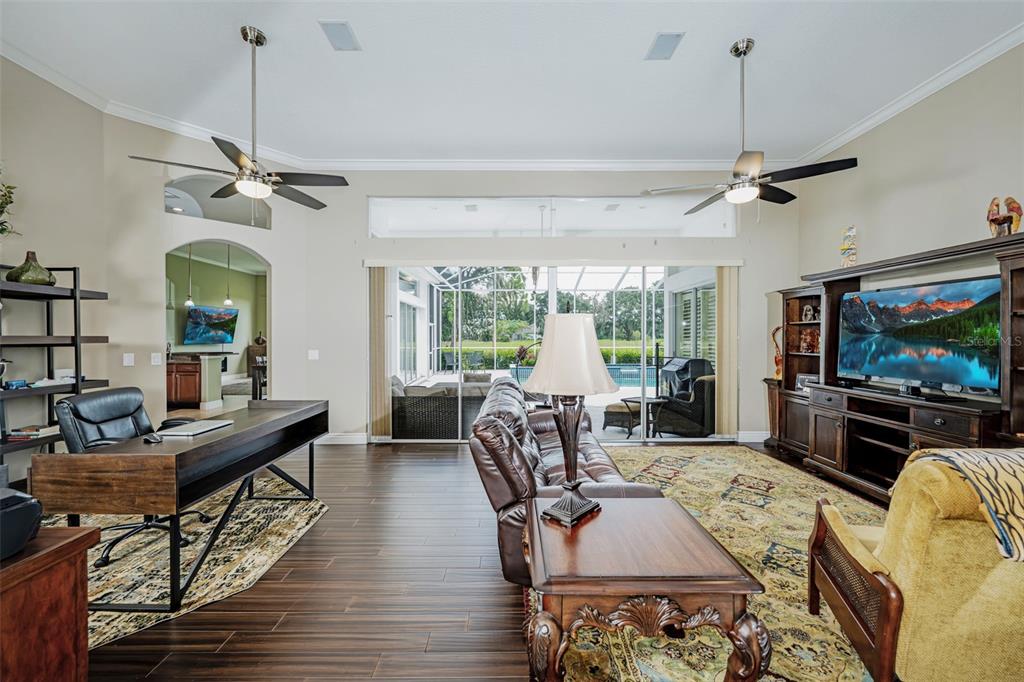 A spacious living room features dark wood flooring, a desk area, and sliding glass patio doors — 5429 BURNT HICKORY DRIVE, VALRICO, FL