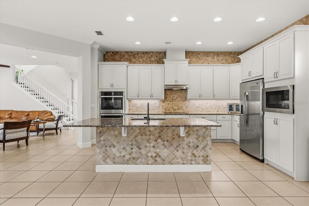A kitchen with white cabinets, granite countertops, a tiled island, and stainless steel appliances — 12837 BOVET AVENUE, ORLANDO, FL