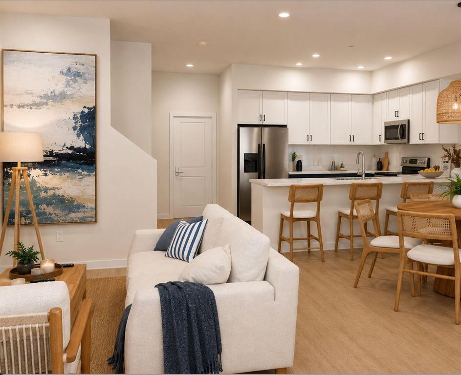 An open-concept living room and kitchen featuring white cabinetry, a breakfast bar, and neutral furniture — 131 TESSIE LANE, SANFORD, FL