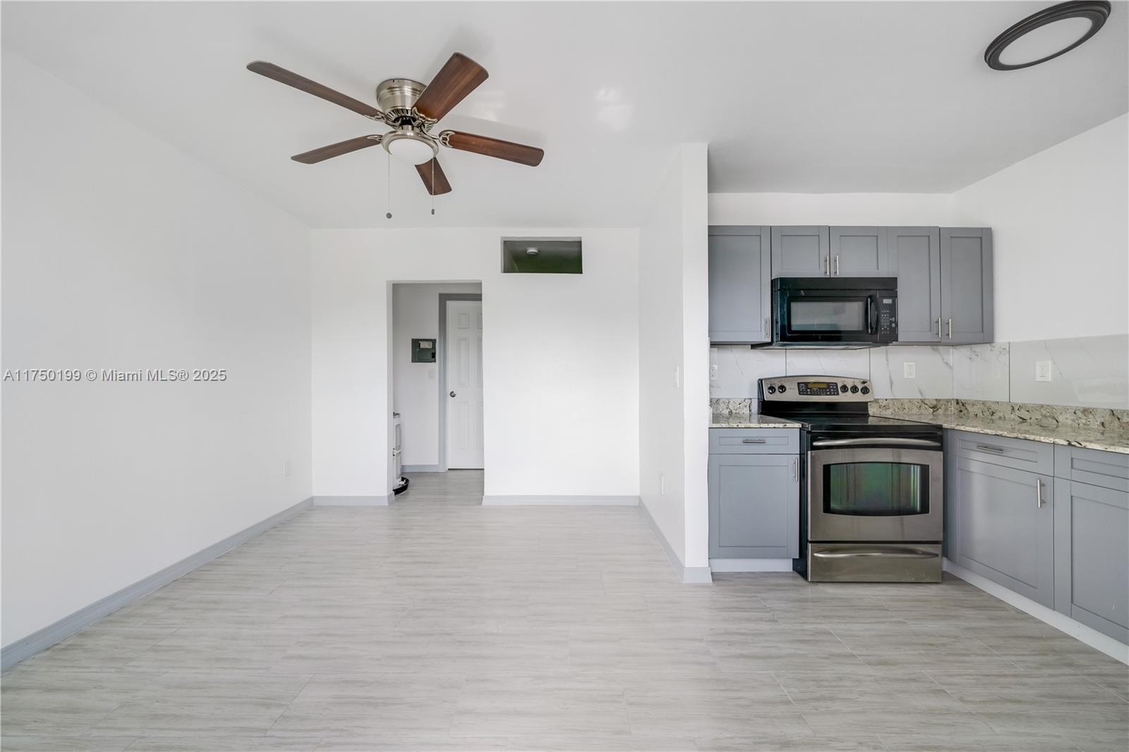 A kitchen with gray cabinets and stainless steel appliances opens into a dining area — 1281 NW 61st St # 2, Miami FL 33142, MIAMI, FL