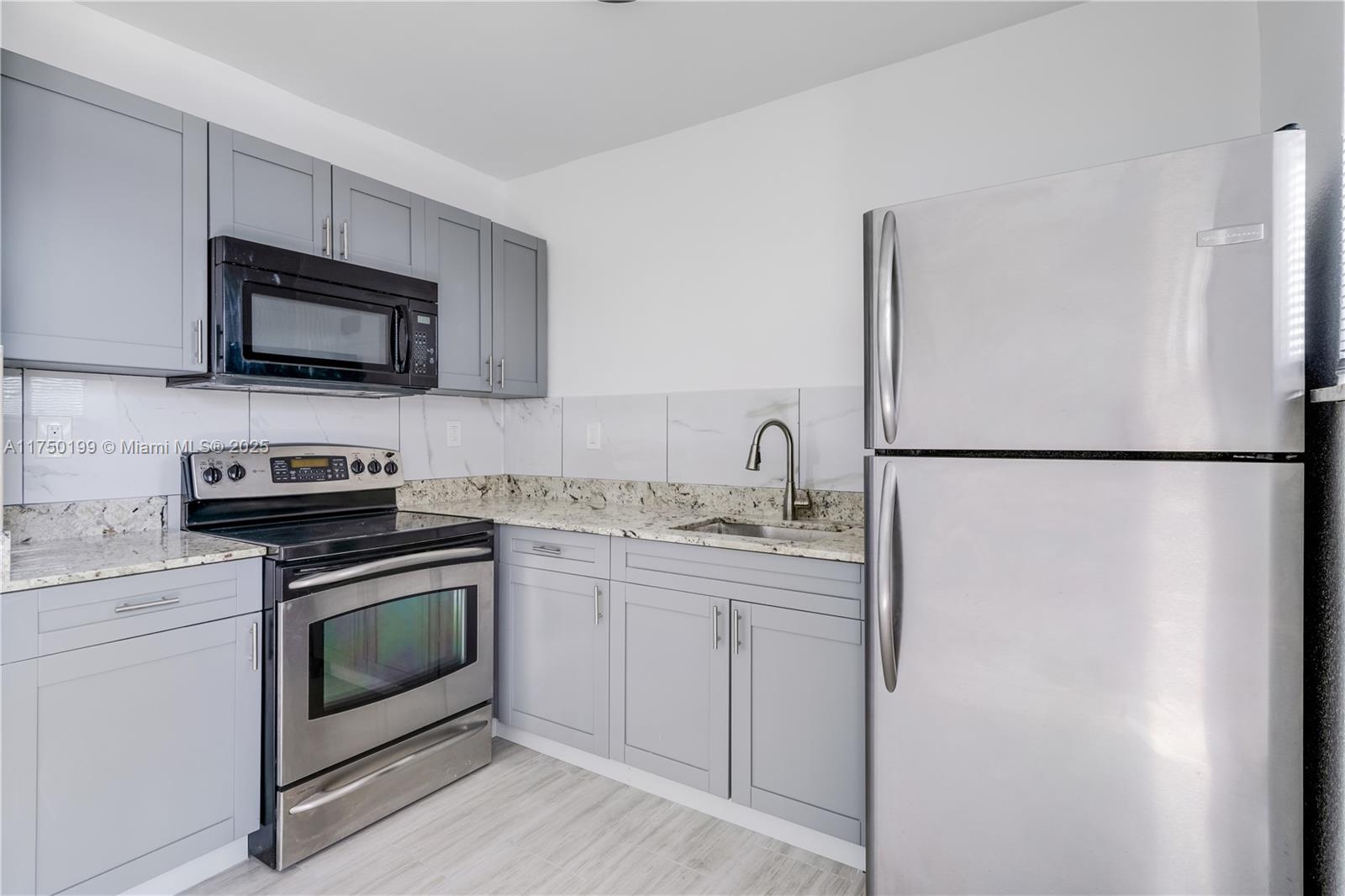 A kitchen features gray shaker cabinets, stainless steel appliances, and granite countertops — 1281 NW 61st St # 2, Miami FL 33142, MIAMI, FL