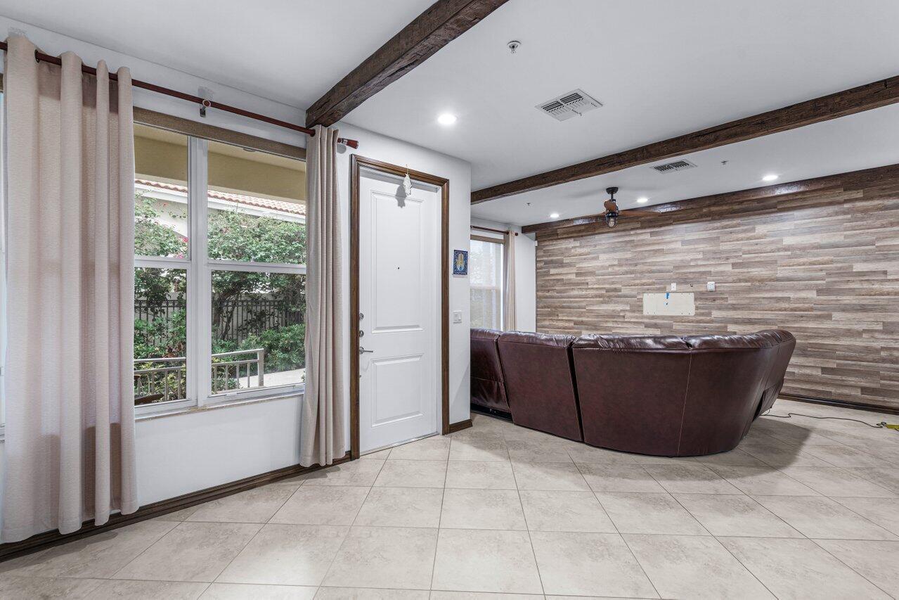 A living room features a wood-paneled accent wall, exposed ceiling beams, and tile flooring — 1511 NW 48th Lane, Boca Raton FL 33431, BOCA RATON, FL