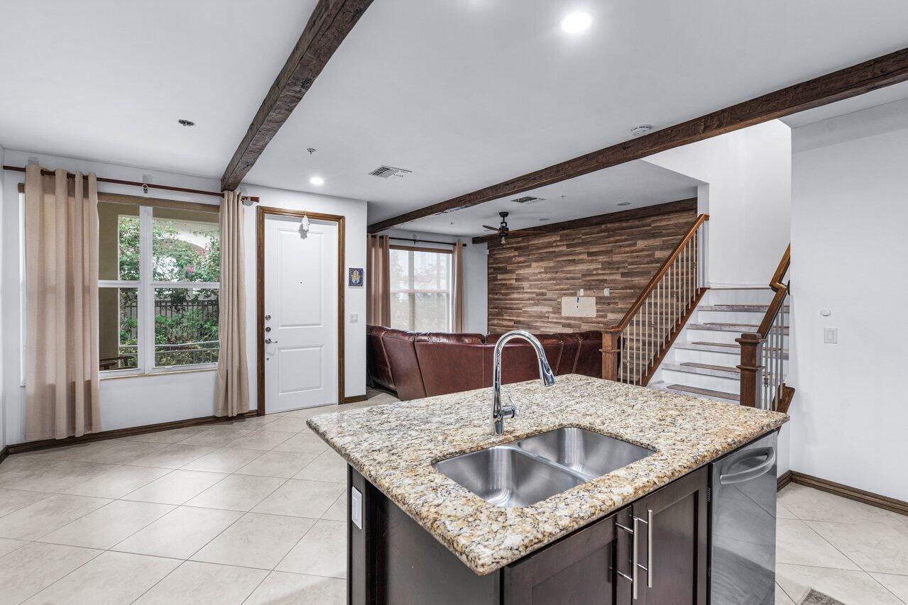 A kitchen island with a granite countertop and sink overlooks a living area with stairs — 1511 NW 48th Lane, Boca Raton FL 33431, BOCA RATON, FL