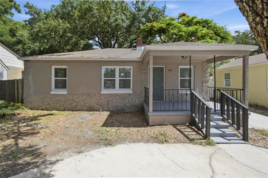 A single-story house with a stone-accented facade, a front porch, and a concrete driveway — 1416 E MOHAWK AVENUE, TAMPA, FL