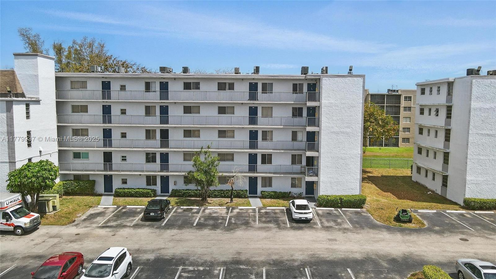 An exterior view of a multi-story apartment building with a parking lot in front — 8540 N Sherman Cir # 408, Miramar FL 33025, MIRAMAR, FL